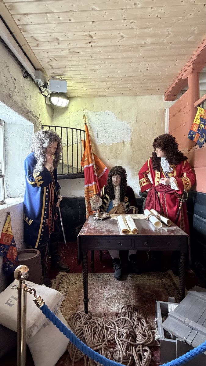 Recreación con figuras de cera de un consejo de guerra jacobita, con banderas y mapas sobre una mesa, en el centro de visitantes de Oldbridge