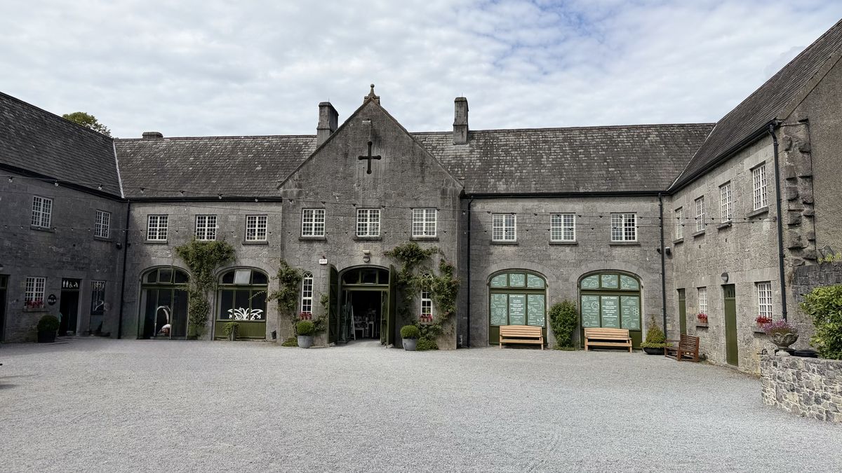 El patio de acceso del Castillo de Birr, con sus edificios de piedra y bancos de madera