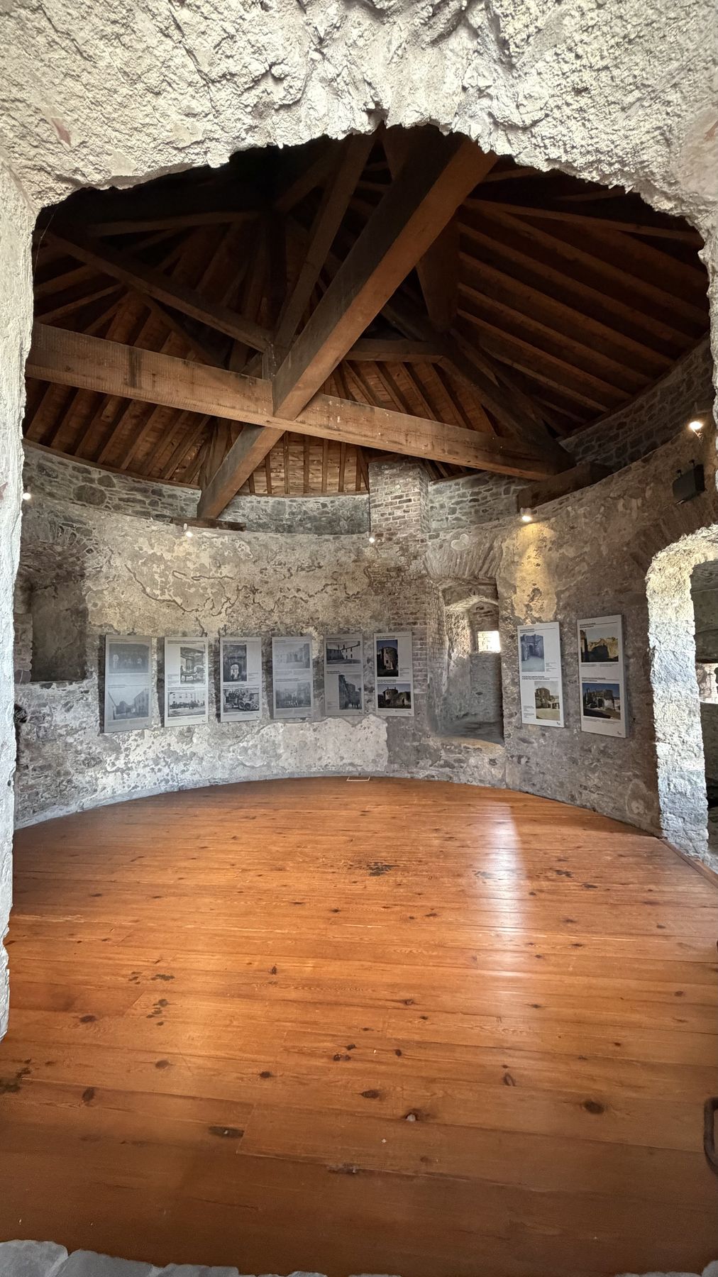 Sala circular con techo de vigas de madera dentro del Castillo de Dungarvan, con paneles informativos