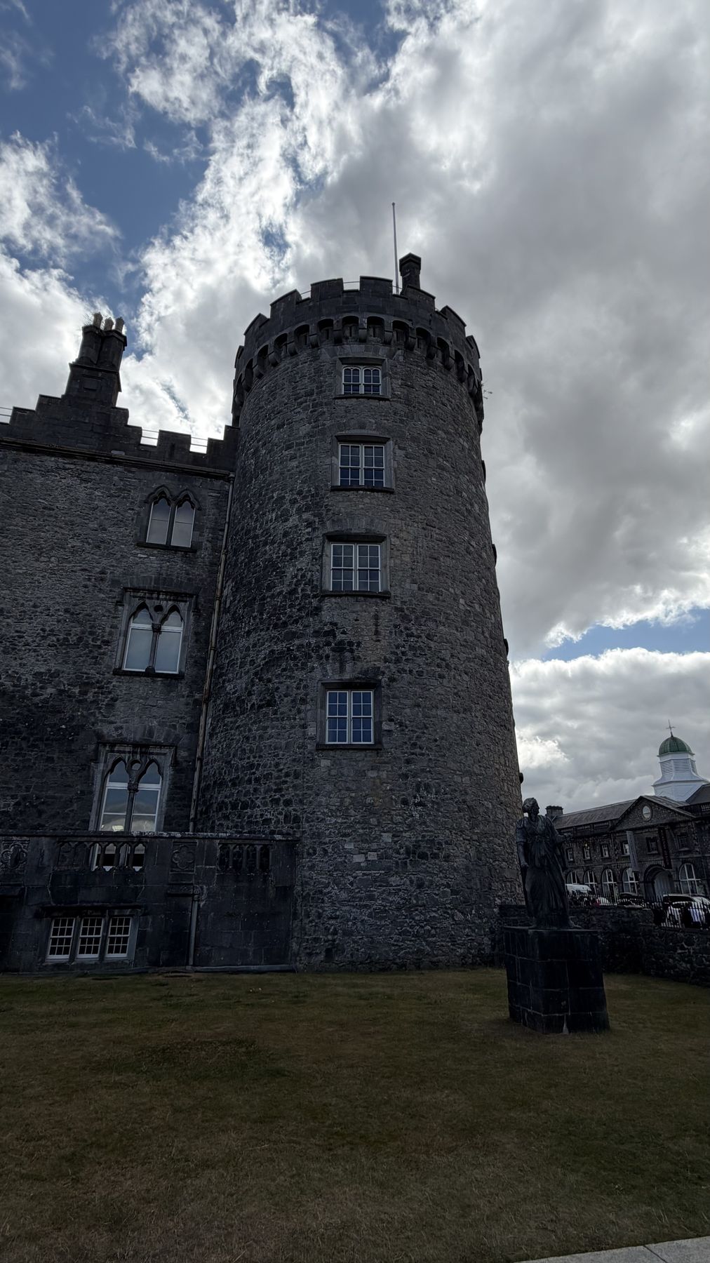 Torre redonda del Castillo de Kilkenny junto a una estatua en el jardín