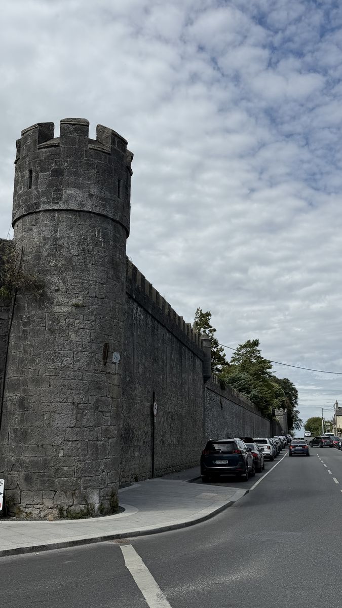Una torre almenada de la muralla del castillo, junto a una calle de Limerick