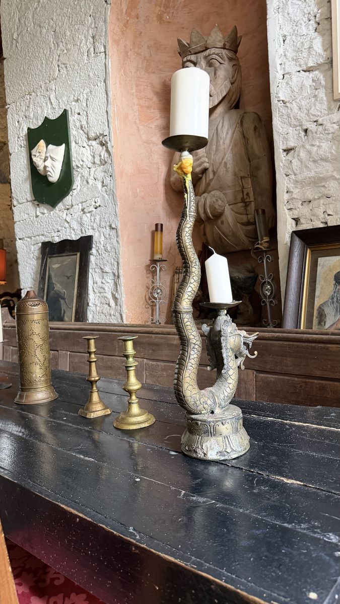 Una chimenea del castillo decorada con candelabros antiguos y una talla de un rey