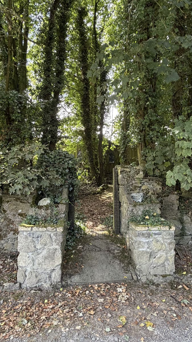 Un portal de piedra entre árboles, camino de acceso al recinto del castillo