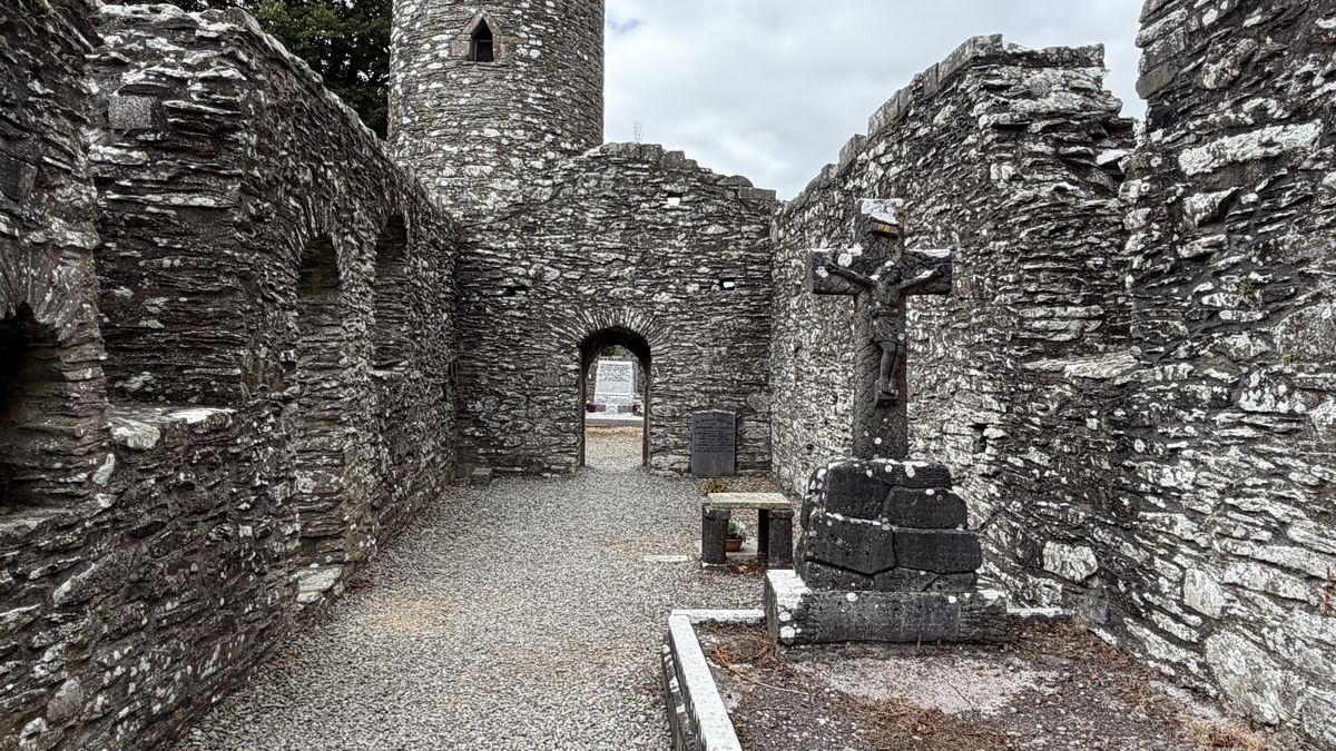 Vista a través de las ruinas de la iglesia sur de Monasterboice hacia una cruz de piedra