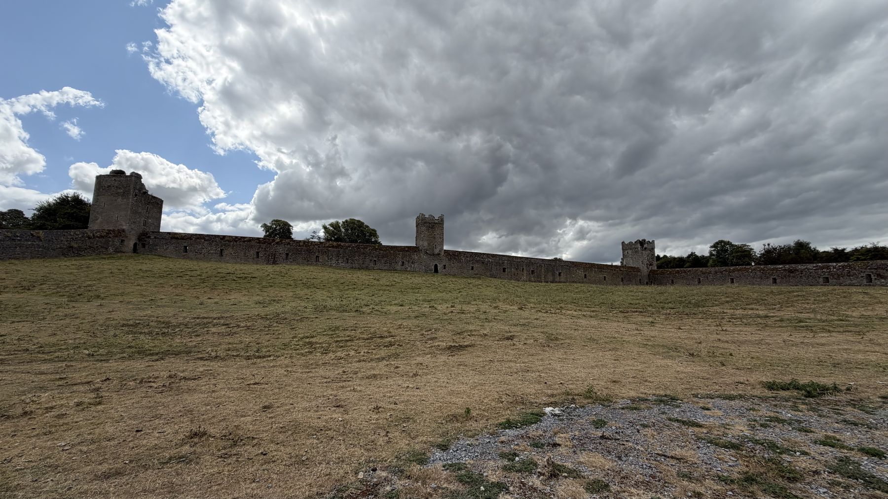 Muralla del Priorato de Kells con sus torres, bajo un cielo nublado
