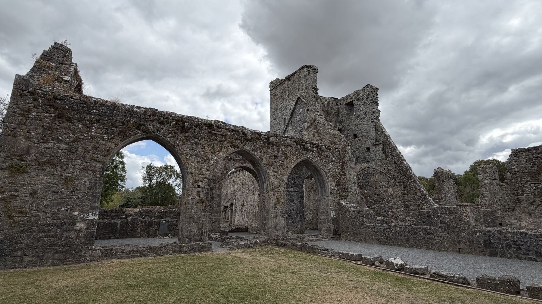 Interior en ruinas del Priorato de Kells, con arcos apuntados y una torre al fondo
