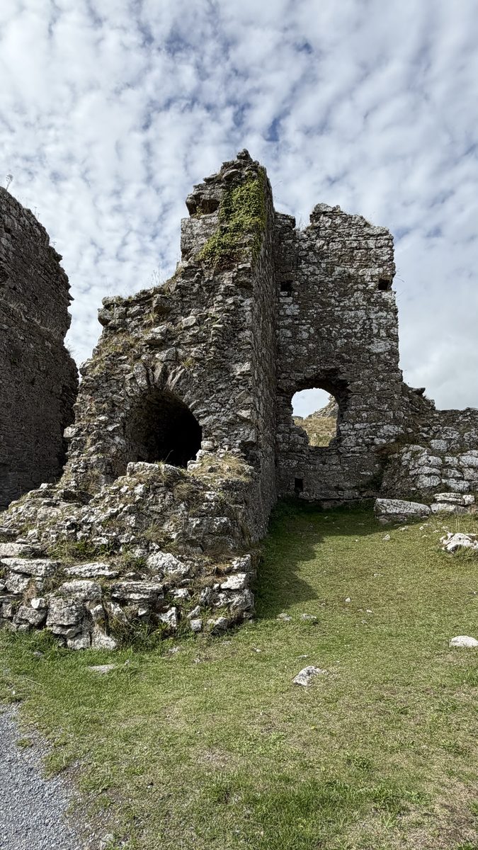 Un arco de piedra en el interior de las ruinas de Dunamase, junto a una torre cubierta de musgo