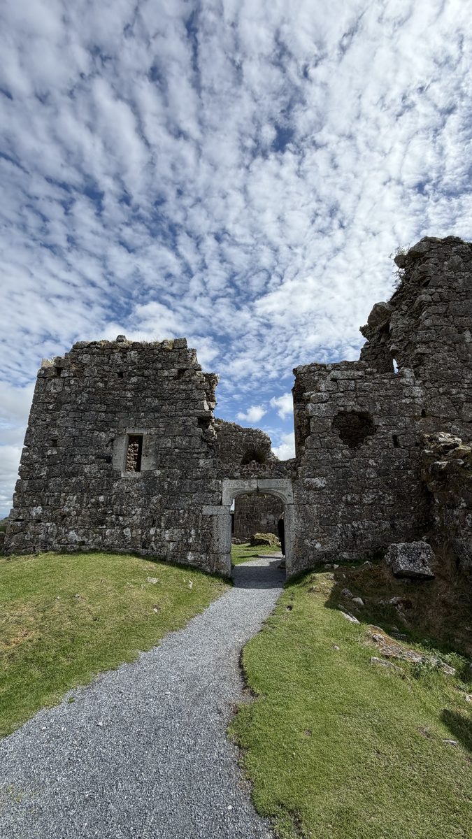 Un sendero de grava pasa por un arco de piedra entre dos torres en ruinas de Dunamase