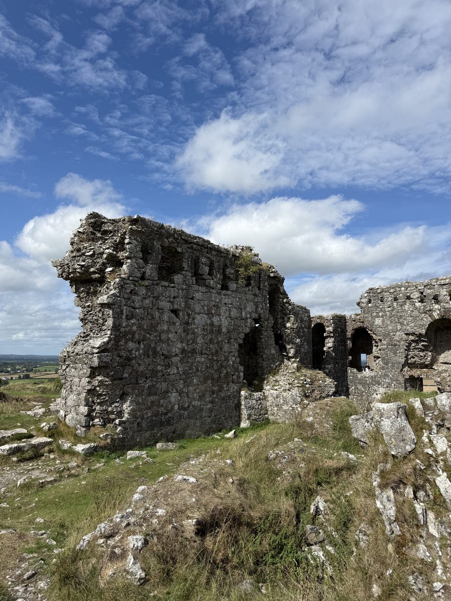 El muro en ruinas de una de las torres de Dunamase, visto desde el exterior, con tierras de labranza al fondo