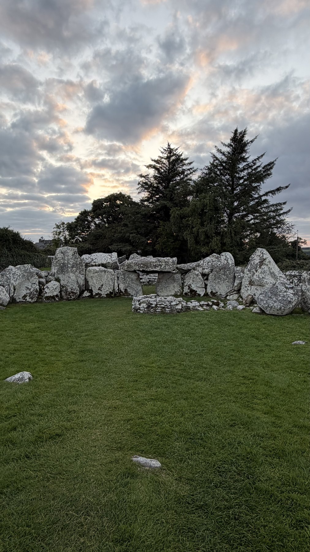 El patio interior de la Tumba de Creevykeel con la cámara funeraria recortada contra el atardecer