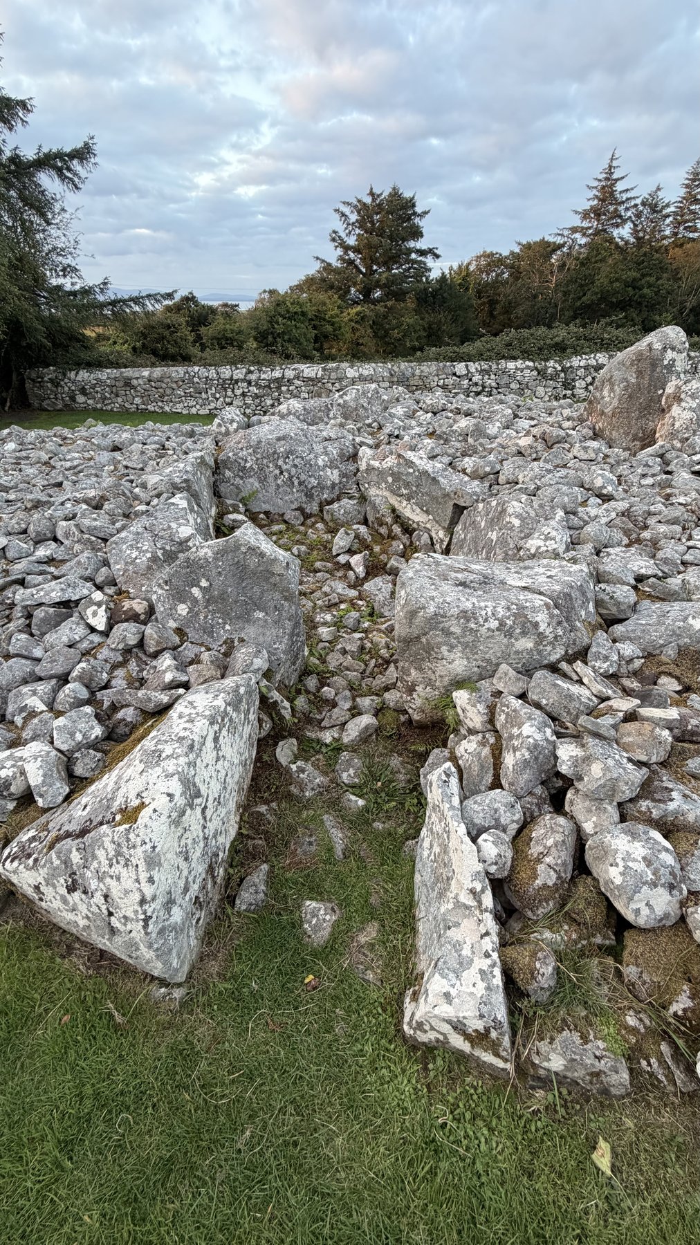 Muro de piedra perimetral de la Tumba de Creevykeel con el paisaje de Sligo al fondo