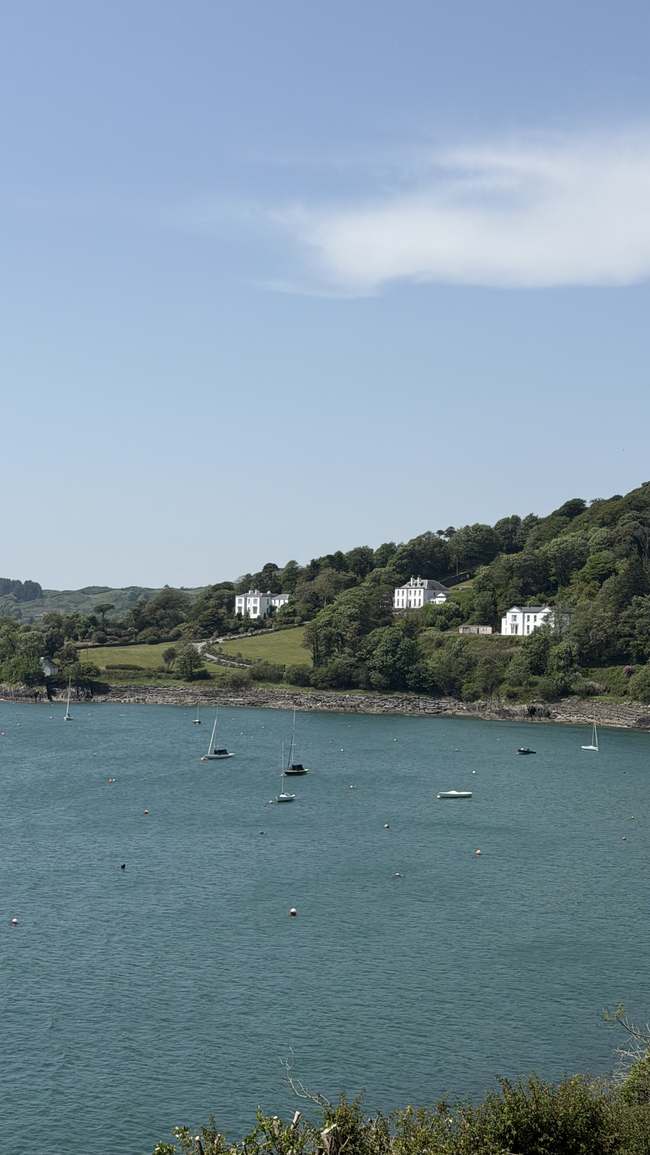 Casas georgianas blancas sobre la bahía de Glandore con veleros anclados
