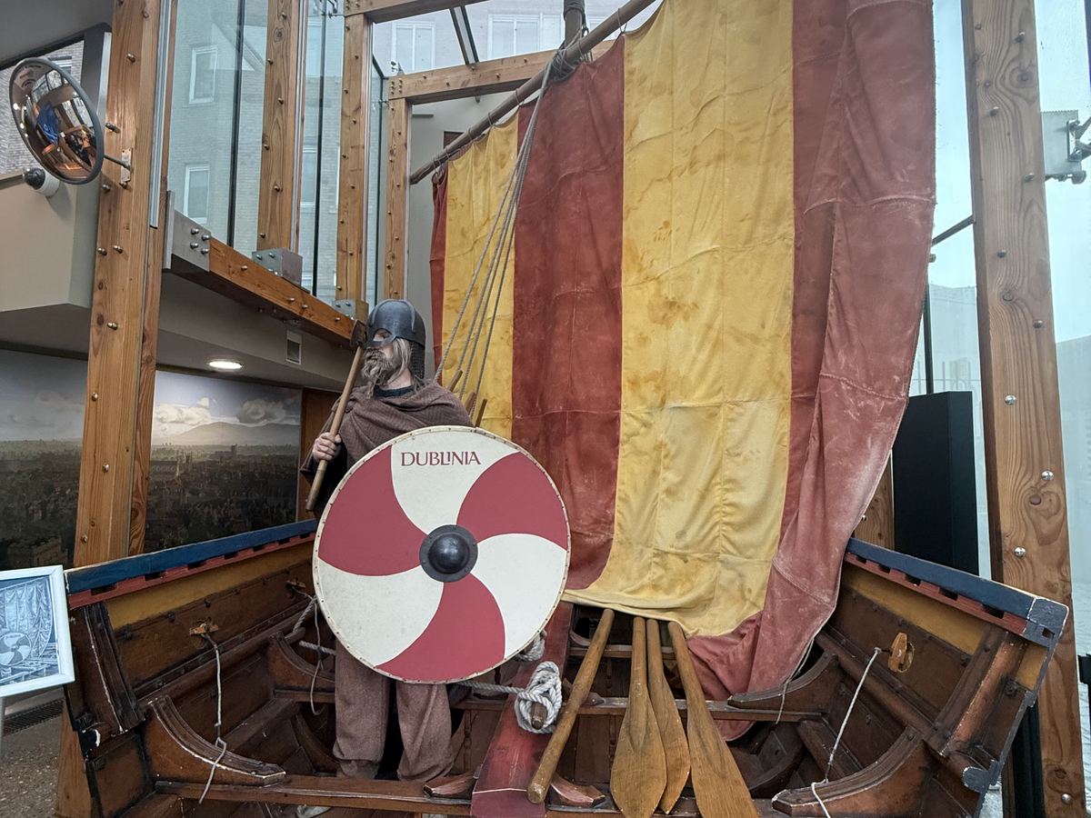 Recreación de un guerrero vikingo junto a un barco replica en el museo Dublinia